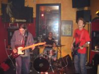 Porth , 2006 © Die Band voll in Aktion. Links spielt Sean seine Gitarre. In der Mitte hinter dem Schlagzeug ist Tobi und rechts im roten T-Shirt groovt Zac den Bass.